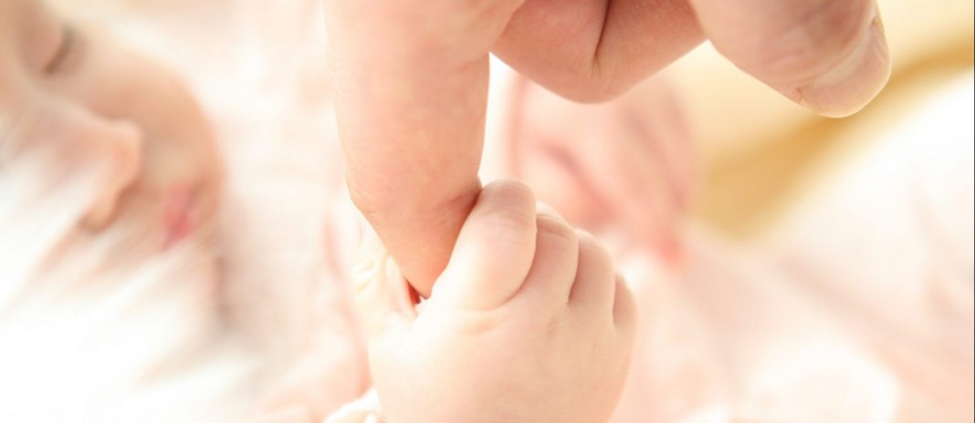 Bebé agarrado al dedo de un adulto